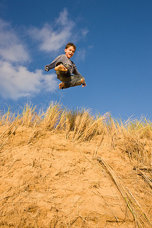 Boy jumping off sand dunes